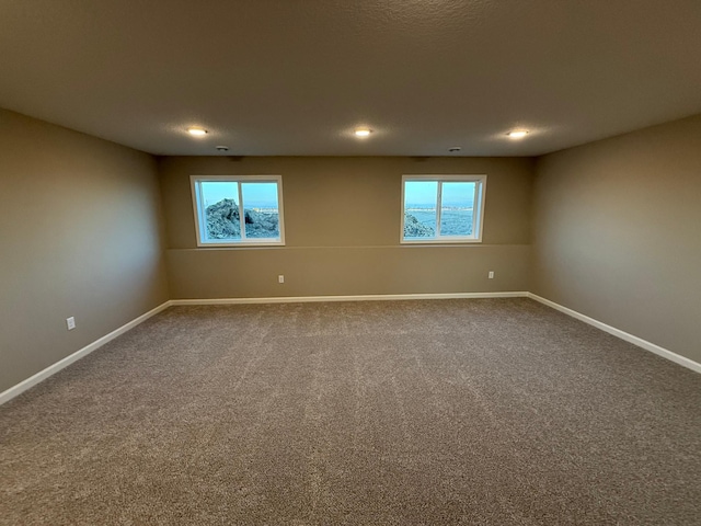 unfurnished room featuring baseboards, dark carpet, plenty of natural light, and recessed lighting