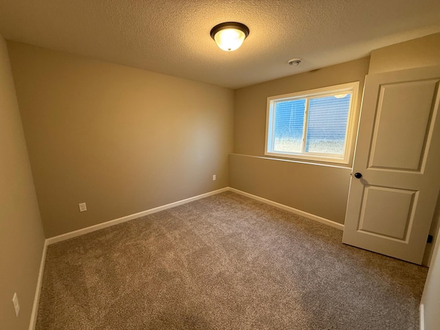 spare room featuring a textured ceiling, carpet, and baseboards