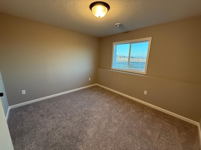 carpeted spare room with a textured ceiling and baseboards