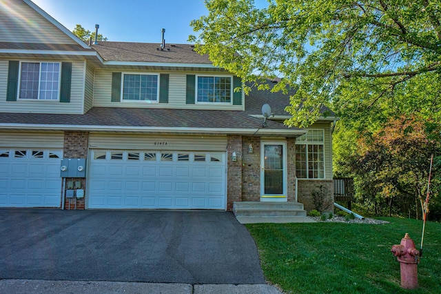 6147 Tahoe Cir Unit A, Woodbury, MN 55125 - view of property featuring driveway, a front lawn, brick siding, an attached garage, and roof with shingles