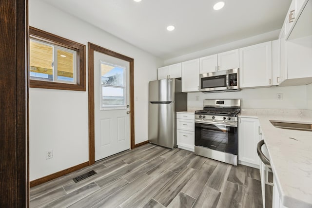 193 Griggs St N, Saint Paul, MN 55104 - kitchen with stainless steel appliances, recessed lighting, light stone countertops, white cabinets, and light wood-style flooring