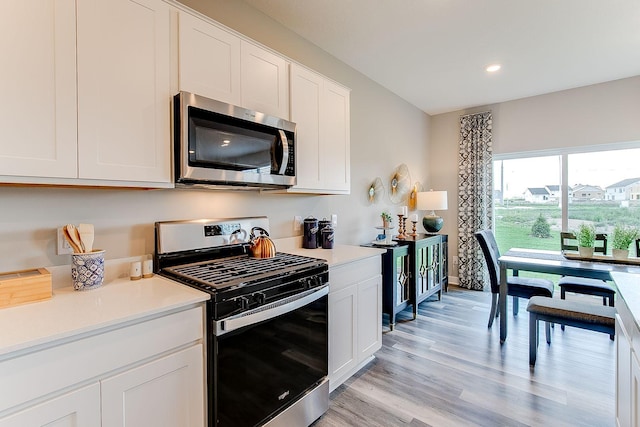kitchen with appliances with stainless steel finishes, light wood-style floors, light countertops, white cabinets, and recessed lighting