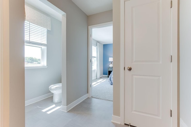 hall with plenty of natural light, baseboards, and light floors