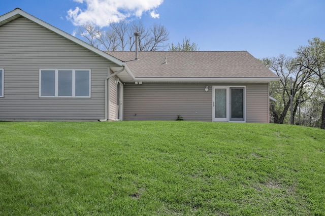 back of house with a yard and a shingled roof