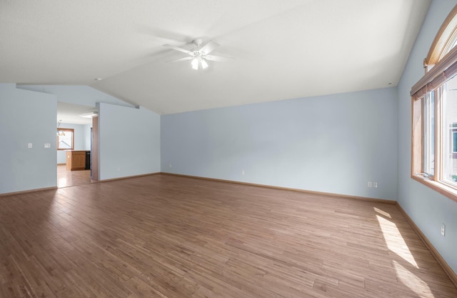 unfurnished living room featuring vaulted ceiling, ceiling fan, light wood-style flooring, and baseboards