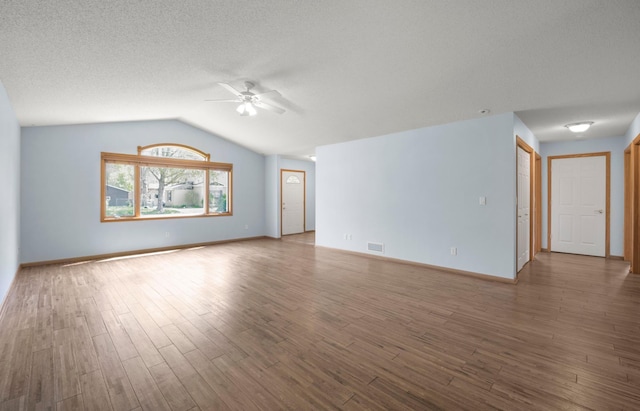 unfurnished living room with a ceiling fan, lofted ceiling, wood finished floors, baseboards, and a textured ceiling