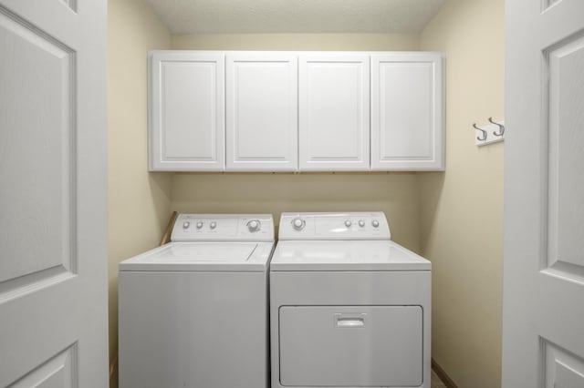 laundry area with separate washer and dryer and cabinet space