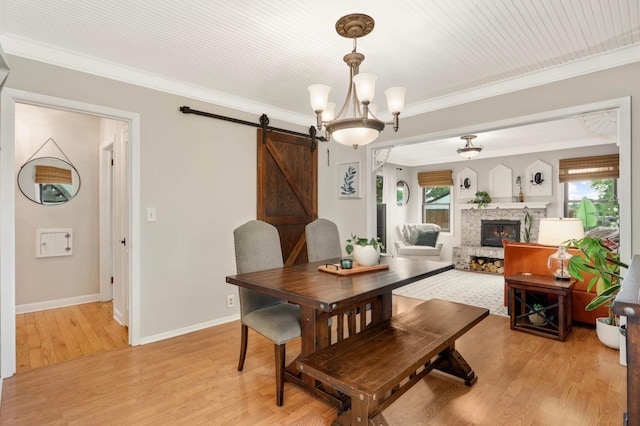 3338 Brownlow Ave, Saint Louis Park, MN 55426 - dining area featuring a barn door, light wood-type flooring, ornamental molding, baseboards, and a stone fireplace
