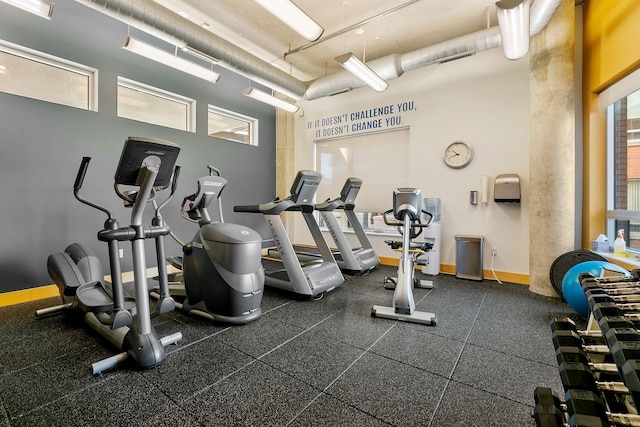 exercise room with a towering ceiling and baseboards