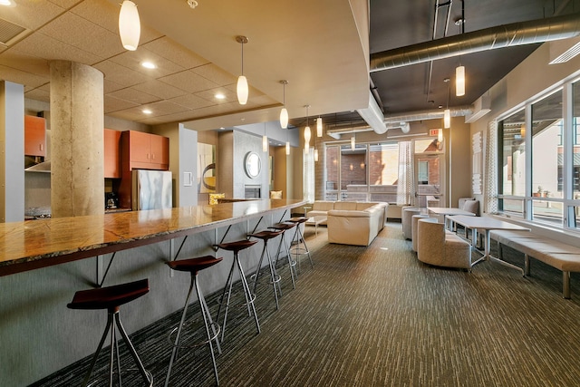 kitchen with freestanding refrigerator, dark carpet, open floor plan, and a breakfast bar area