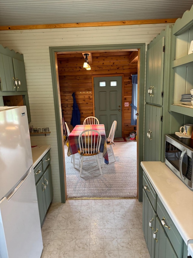 27721 Northwoods Dr, Laporte, MN 56461 - kitchen featuring freestanding refrigerator, wood walls, stainless steel microwave, green cabinets, and light countertops