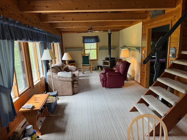 27721 Northwoods Dr, Laporte, MN 56461 - living room featuring a wood stove, beamed ceiling, carpet flooring, wood walls, and stairs