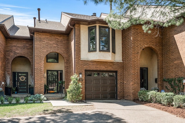1940 Dupont Ave S, Minneapolis, MN 55403 - view of front of property featuring driveway, an attached garage, a shingled roof, stucco siding, and brick siding