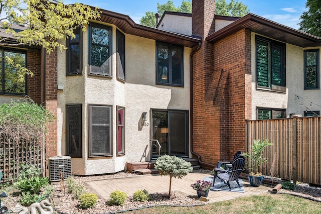1940 Dupont Ave S, Minneapolis, MN 55403 - rear view of property with a chimney, fence, central air condition unit, stucco siding, and entry steps