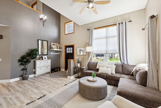 living area with high vaulted ceiling, ceiling fan, wood finished floors, and baseboards