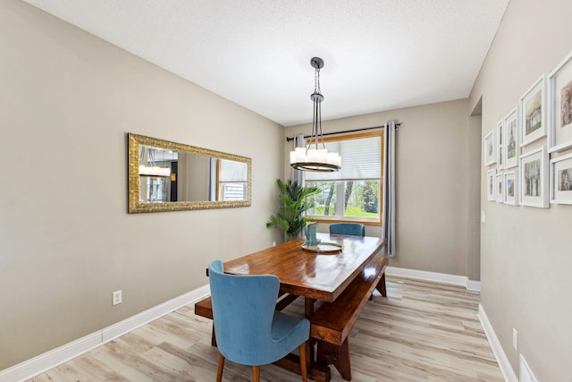 dining area featuring light wood finished floors, a chandelier, and baseboards