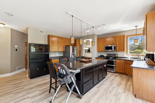 kitchen featuring stainless steel appliances, a center island, light wood-style floors, and a sink