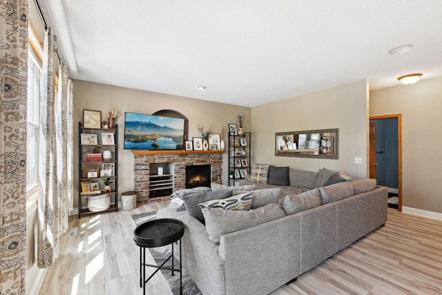 living area with wood finished floors, a warm lit fireplace, and baseboards