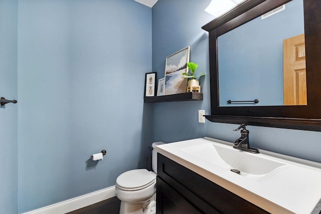 bathroom featuring toilet, vanity, and baseboards