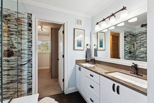 bathroom featuring a stall shower, crown molding, wood finished floors, double vanity, and baseboards