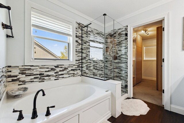 bathroom featuring wood finished floors, a stall shower, a garden tub, and crown molding