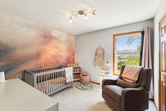 carpeted bedroom featuring a crib, a textured ceiling, and baseboards