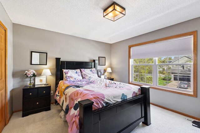 bedroom featuring light carpet, a textured ceiling, and baseboards