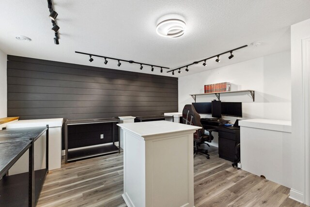 home office featuring rail lighting, light wood finished floors, and a textured ceiling