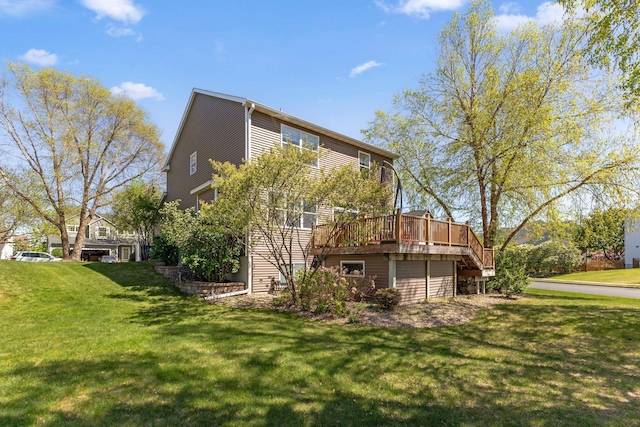 rear view of house featuring a deck, a yard, stairway, and an attached garage