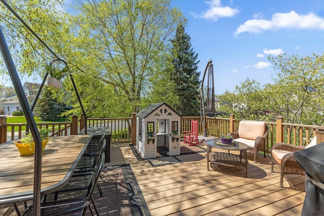 wooden terrace featuring outdoor dining area, a shed, outdoor lounge area, and an outbuilding