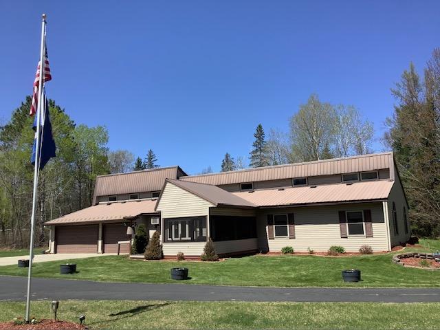 19323 Wendigo Park Rd, Harris Twp, MN 55744 - view of front of property with a front lawn, a garage, a sunroom, and metal roof