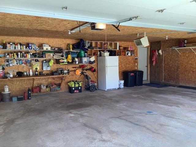 19323 Wendigo Park Rd, Harris Twp, MN 55744 - garage with freestanding refrigerator, a garage door opener, and a workshop area