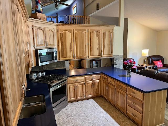 19323 Wendigo Park Rd, Harris Twp, MN 55744 - kitchen with appliances with stainless steel finishes, backsplash, dark countertops, and open floor plan
