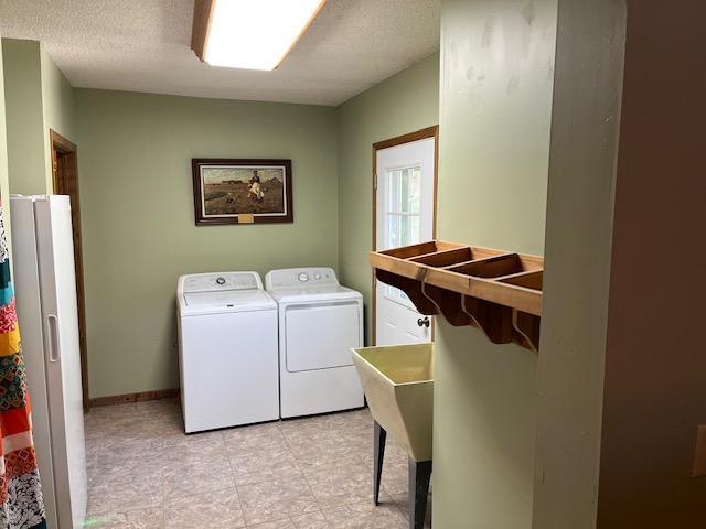 19323 Wendigo Park Rd, Harris Twp, MN 55744 - laundry area featuring washing machine and clothes dryer, baseboards, a textured ceiling, and light tile patterned flooring