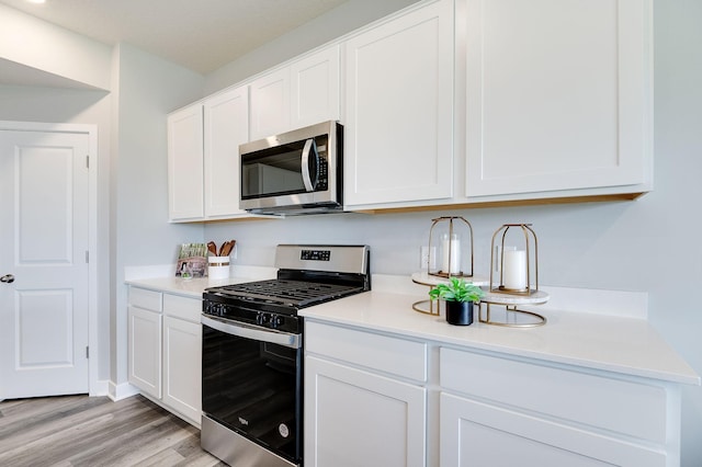 kitchen featuring appliances with stainless steel finishes, white cabinets, light countertops, and light wood-style flooring