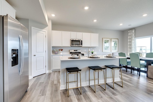 kitchen featuring stainless steel appliances, light wood-style flooring, white cabinets, and recessed lighting