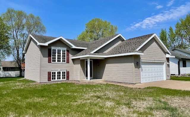 split level home featuring a garage, a front lawn, roof with shingles, and driveway