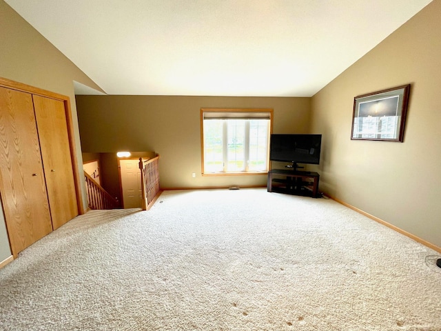 unfurnished living room featuring lofted ceiling, carpet flooring, and baseboards