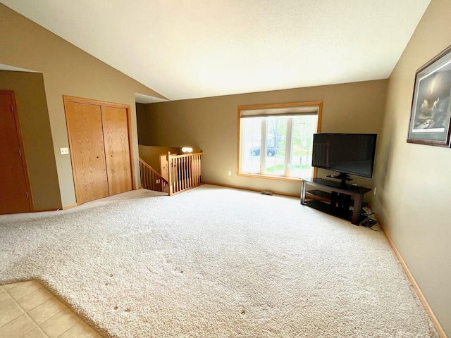 unfurnished living room featuring vaulted ceiling, light carpet, and baseboards