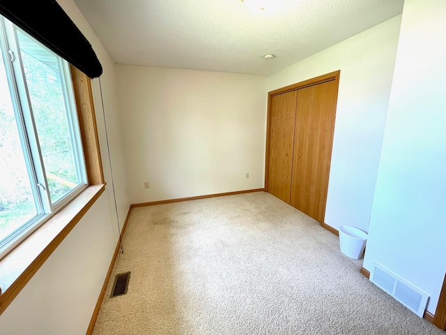 unfurnished bedroom with light colored carpet, a closet, and baseboards