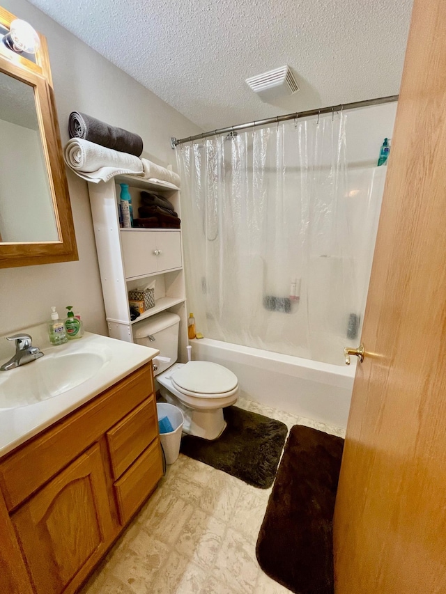 full bathroom featuring a textured ceiling, shower / tub combo with curtain, vanity, toilet, and tile patterned floors