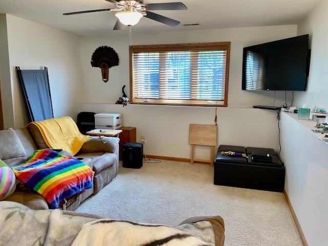 carpeted living area with ceiling fan and baseboards