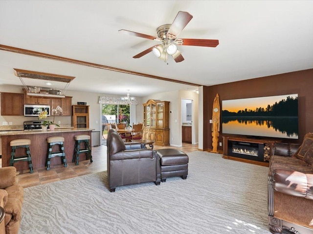 living room featuring a ceiling fan, a glass covered fireplace, and a chandelier