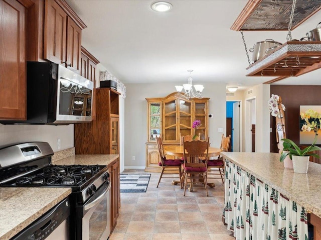 kitchen with appliances with stainless steel finishes, a chandelier, brown cabinetry, baseboards, and recessed lighting
