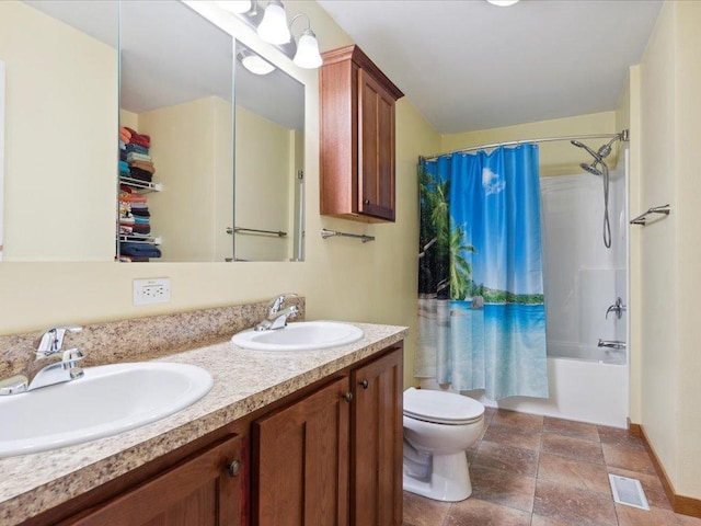 bathroom featuring toilet, stone finish flooring, double vanity, and shower / tub combo
