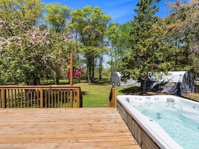 wooden terrace featuring a hot tub, a lawn, and view of scattered trees