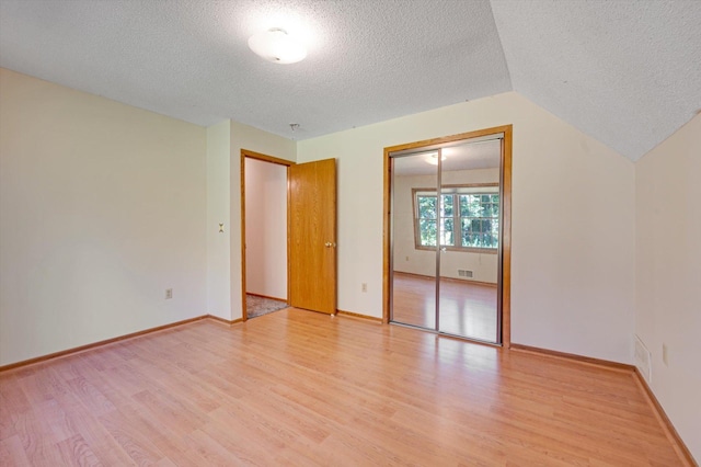 771 County Road B2 E, Little Canada, MN 55117 - unfurnished bedroom with a textured ceiling, light wood-style floors, baseboards, and vaulted ceiling
