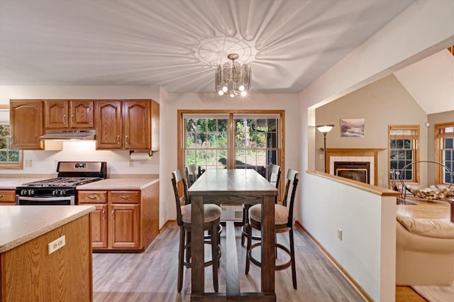 771 County Road B2 E, Little Canada, MN 55117 - kitchen with stainless steel gas stove, light wood finished floors, light countertops, a chandelier, and under cabinet range hood