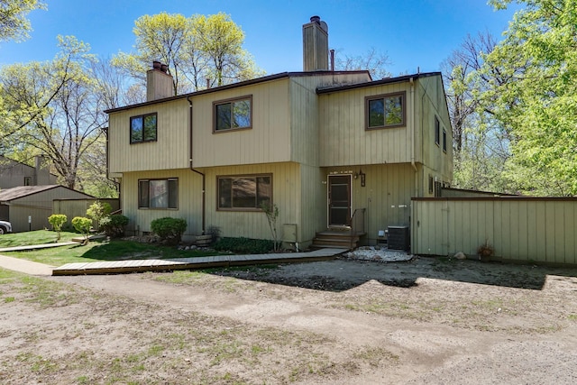 back of house featuring a chimney, entry steps, and central air condition unit