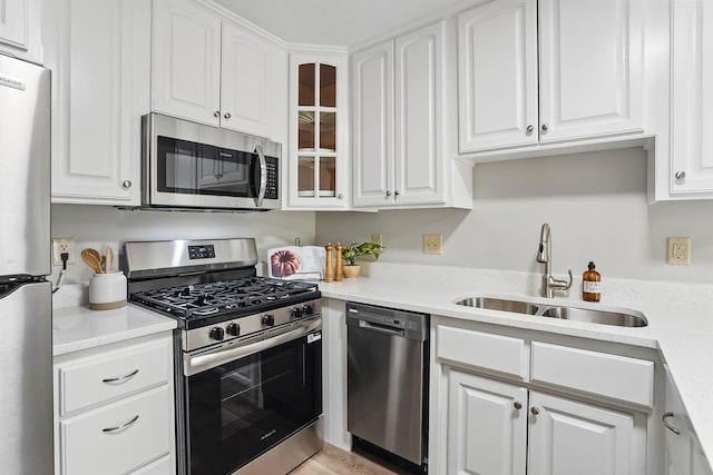 kitchen featuring stainless steel appliances, a sink, and white cabinetry